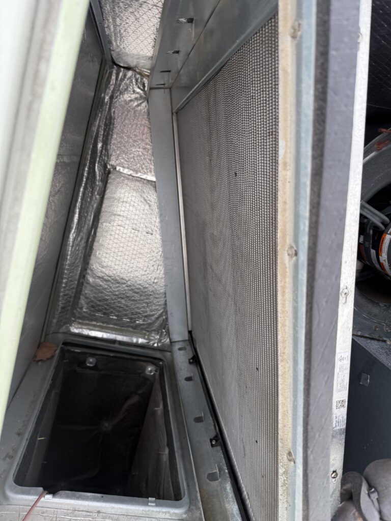 Inspecting the coil section inside a commercial rooftop HVAC unit during maintenance