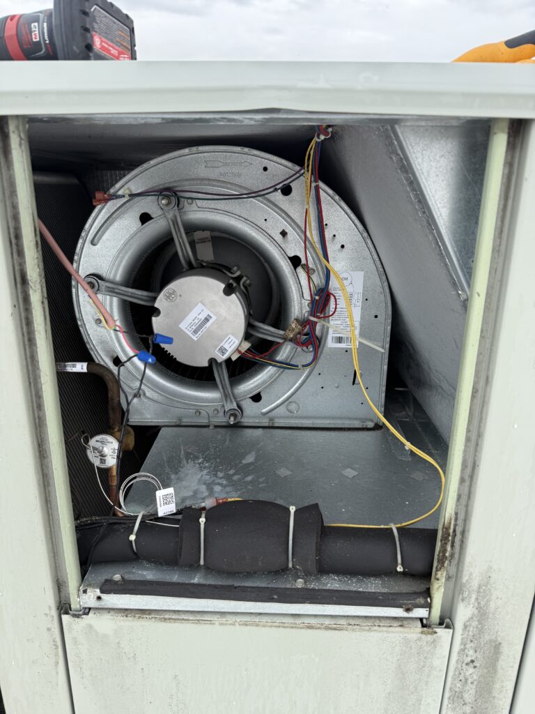 Blower motor and wheel inspected inside a commercial rooftop unit during preventative maintenance