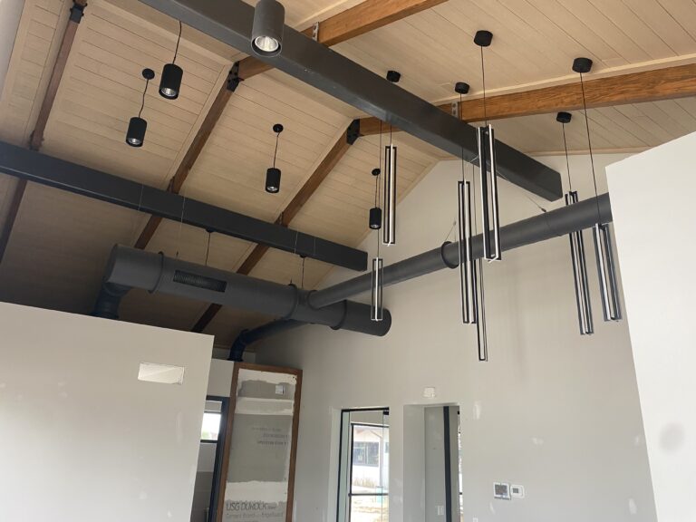 Clean, level exposed black metal ductwork under a wood ceiling in a new commercial office built for Capling Leveling