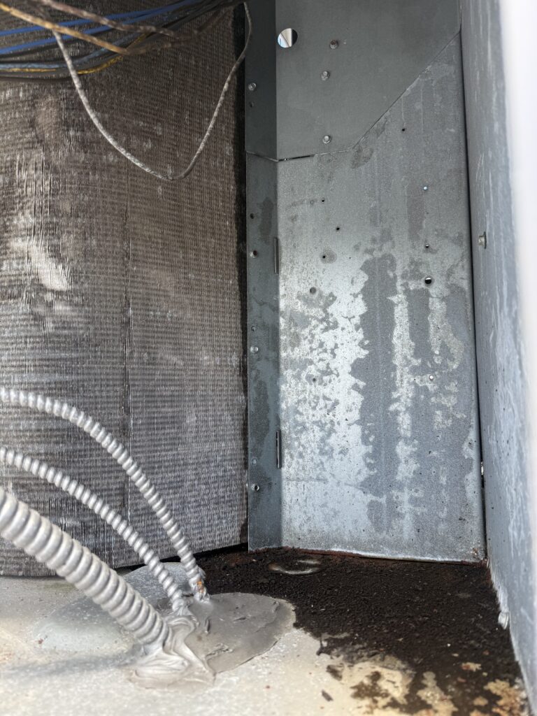 Oil-stained condenser coil showing a refrigerant leak on a commercial rooftop unit at a Naples, FL dental office
