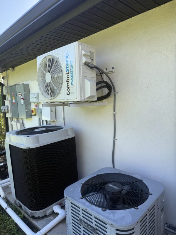 Ductless mini-split outdoor condenser mounted on a wall bracket beside the home’s central AC units, installed by Extreme Temp in Southwest Florida