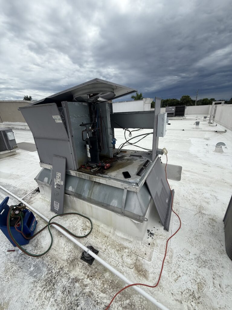 Extreme Temp technicians replacing the condenser coil on a commercial rooftop unit (RTU) at a dental office in Naples, FL