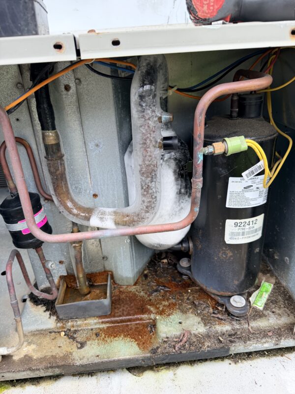 Ice frozen on the suction line and accumulator next to the compressor of an outdoor AC unit, a sign of a frozen air conditioner, found by Extreme Temp Air Conditioning & Heating in Southwest Florida