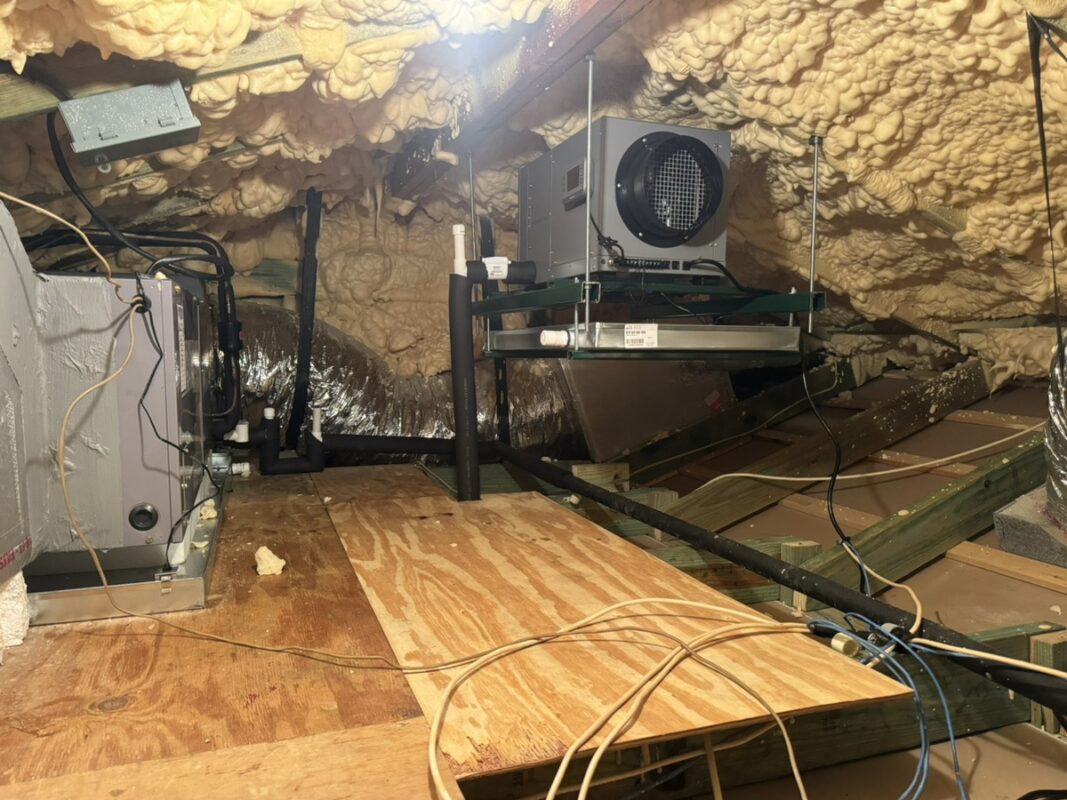 Dehumidifier mounted on a stand in a spray foam attic to control attic humidity, installed by Extreme Temp