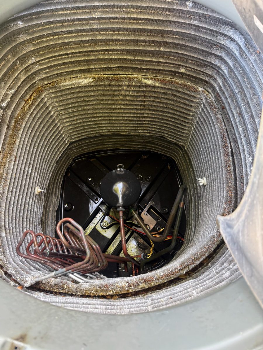 Looking down into an outdoor AC condenser at the compressor, base pan and coil during an Extreme Temp maintenance visit